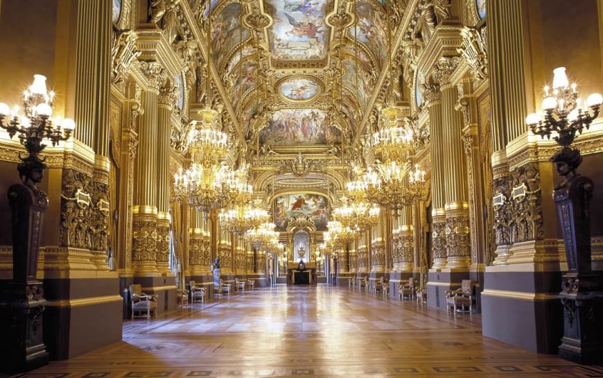 Dans le grand foyer, le jeu des miroirs et des fenêtres accentue encore ses vastes dimensions. Le plafond peint par Paul Baudry (1828-1886) décline des thèmes de l’histoire de la musique.