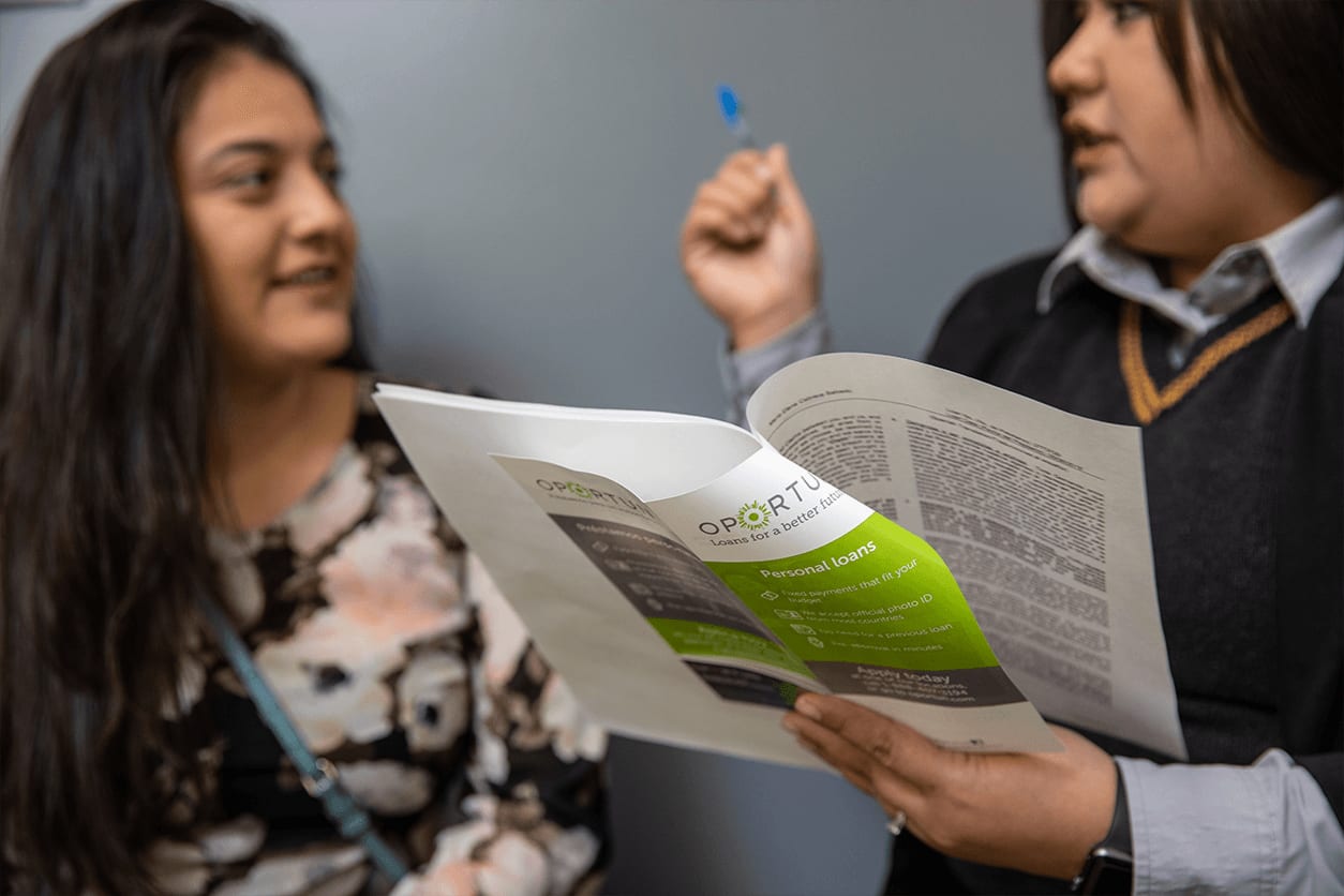 Photo of an Oportun employee revieweing a loan contract with a new customer