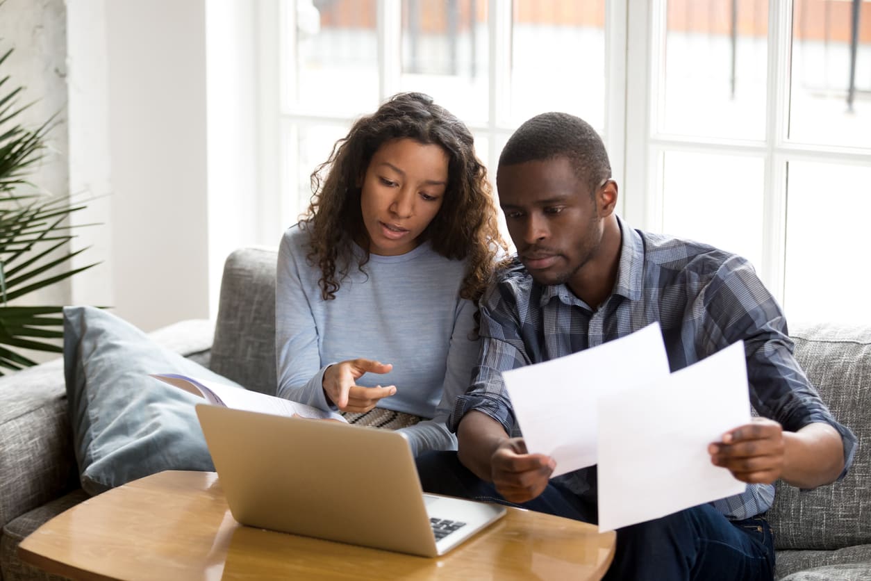 Serious couple discussing paper documents, checking bills, bank account balance, terms of contract, loan agreement