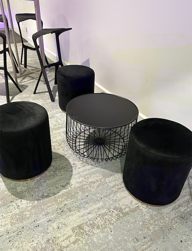 Black wire round coffee table next to black ottoman stools