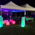 Glow Pillar Hire - A tent with colorful lights and a table in the grass.