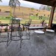 A black table and chairs on a patio with a view of a field.