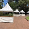 A fete stall set up with white tents on a brick walkway.