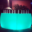 A curved green LED bar with glowing bottles on top.