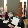 A table with a small commercial chocolate fountain and candy on it.