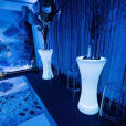 A room with vases and clear ghost stools against a blue background.