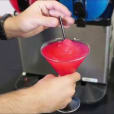 A person pouring *60 drinks* into a machine.