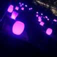 A group of purple stools in a dark area available for Glow Bongo Seat Hire.