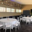 A room with round timber banquet tables and chairs set up for a party.