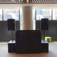 A room with two speakers on speaker stands in front of a large window available for hire.