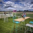 Turquoise blue chairs are set up on a grassy field along with a table.