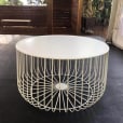 A white wire coffee table with a basket on top.