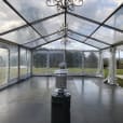 A clear tent with a chandelier hanging in the middle, perfect for luxurious events in framed marquees.