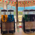 Two Slushie Machine drinks are sitting on a table in front of a window, offering a refreshing selection of 240 drinks.