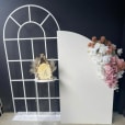 A white French window frame with a vase and flowers on a backdrop.