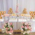 A dessert table adorned with cupcakes and flowers, featuring a Clear Acrylic Ghost Table.