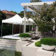 A modern backyard with a white tent and potted plants, featuring a 3mx3m Pop Up Marquee with a White Roof.