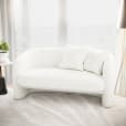 A white bouclé 2-seater sofa in front of a window.