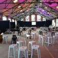 A large warehouse filled with tables, chairs, and white Tolix stool hire options.