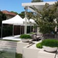 A modern backyard with a white 3mx3m pop-up marquee tent and potted plants.