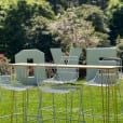 A high bar table with chairs and a love sign in the grass.