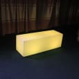 A yellow LED cube sitting on a carpeted floor, emitting a captivating glow.