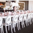 A table set up with white Victorian chairs and a white tablecloth.