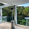 A balcony with a table, chairs, and a gas heater.