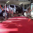 A car is parked on a red carpet in a parking lot for a special event.