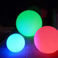 A group of colorful 40cm lighted balls on a concrete floor.