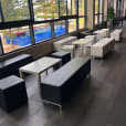 A group of black benches in a room with large windows.