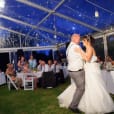 A bride and groom sharing their first dance under the romantic ambiance of white rice lanterns in a tent.