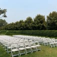 A stunning lawn decorated with white padded folding chairs set up for a beautiful wedding ceremony.