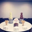 Three chocolate fountains on a table in a conference room, surrounded by wafer biscuits.