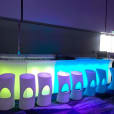 A vibrant bar set up with colorful lights and stools available for Glow Stool Hire.