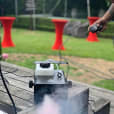 A man utilizing a smoke machine on a wooden deck for an unforgettable ambiance at a Smoke Machine Hire event.