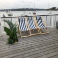 Three deck chairs on a deck overlooking the water hired from Party Hire Group