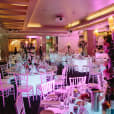 A large room with round glow banquet tables and chairs set up for a wedding.