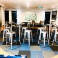 A group of stainless steel cocktail bar tables in a room with a blue checkered floor.