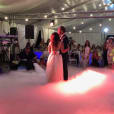 A bride and groom gracefully dancing on a cloud of smoke created by a professional dry ice machine operator.