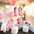 A room filled with pink and white balloons, enhanced with a white ottoman cube hire.