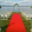 A wedding ceremony set up on a red carpet in front of a lake, featuring a stunning 7m long red carpet.