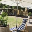 A blue and white striped deck chair under an umbrella.