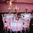 A square room with white tables and chairs hired for an exquisite banquet.