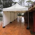 A 4mx8m white tent is set up in a rainy courtyard, featuring walls on 3 sides.