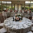 A table set up with white Tiffany chairs and flowers.