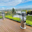 A wooden deck with two outdoor heaters and a city view.