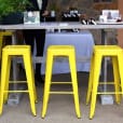 A group of yellow Tolix stools in front of a table.