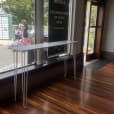 A high bar table with a white top placed in front of a window in a building.