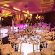 A room with round glow banquet tables and chairs set up for a wedding.